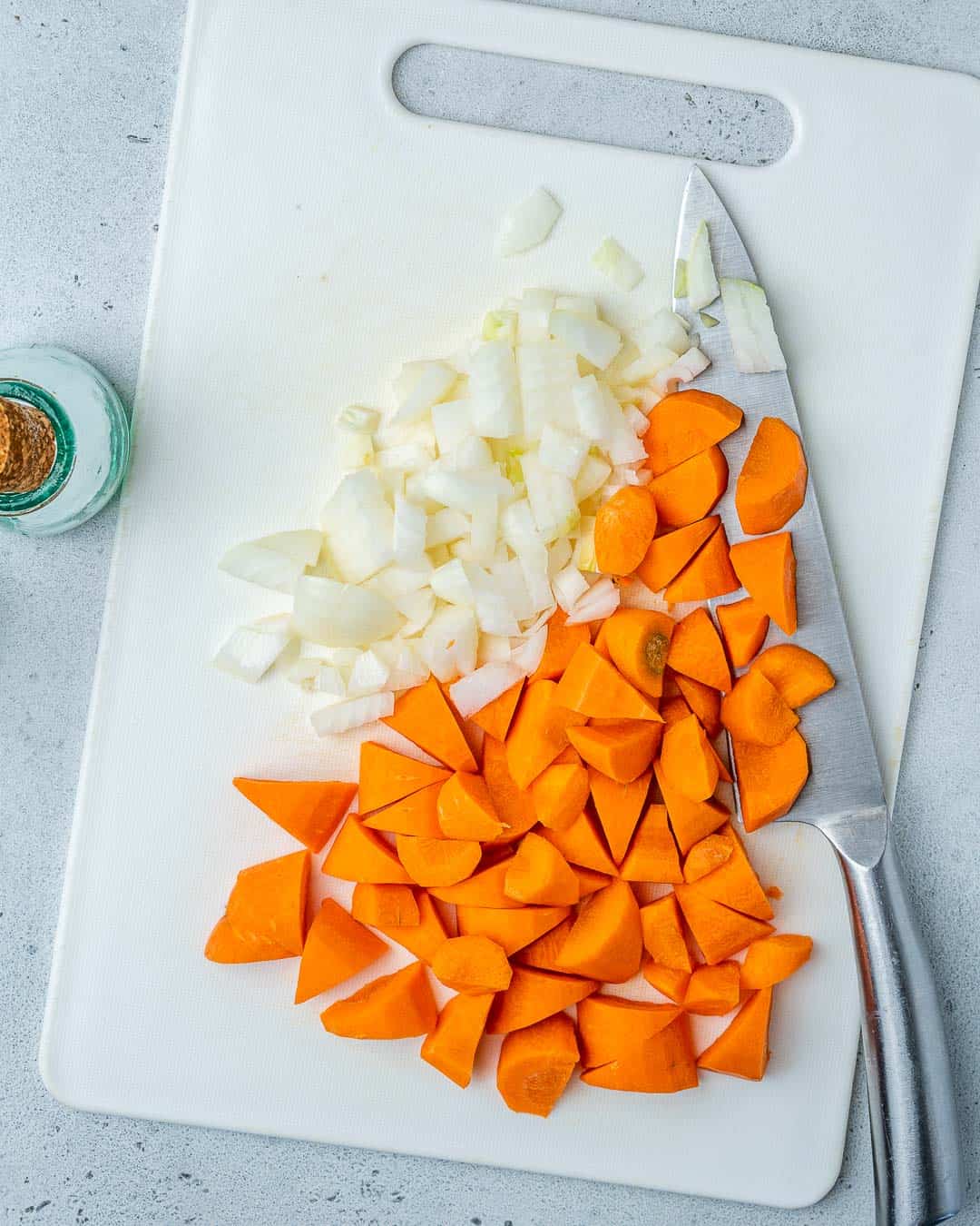 Carrots and onions chopped on cutting board for vegan lentil soup