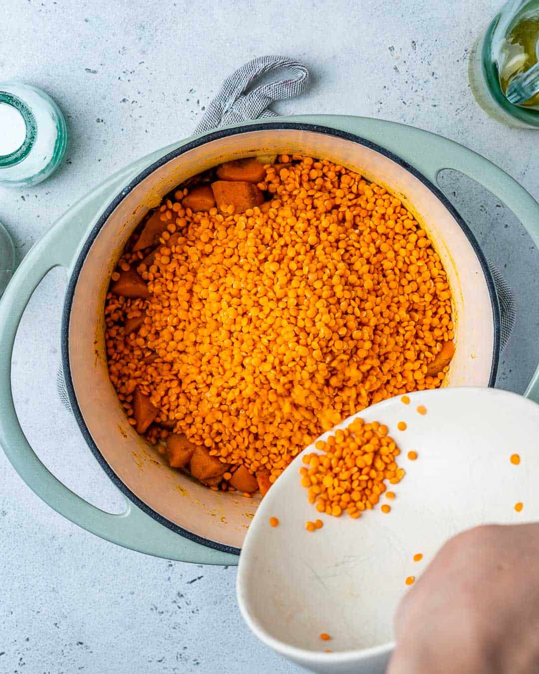 Red lentils being poured in pot to make red lentil soup