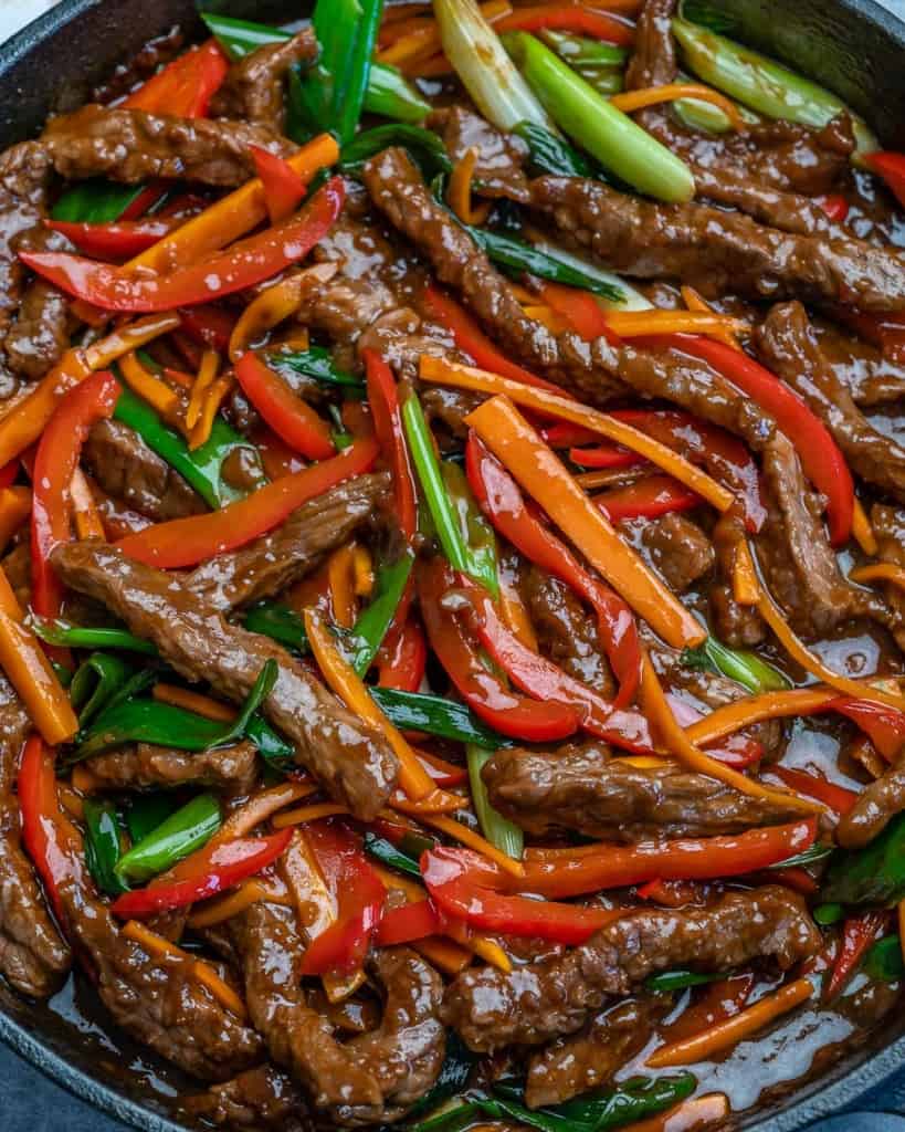 close up view of sauteed beef stir fry with carrots, red peppers, and green onions