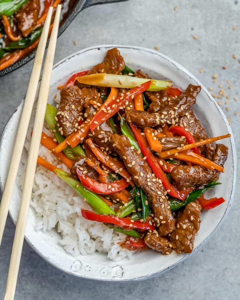 top view of a round white bowl with rice and sauteed beef with veggies