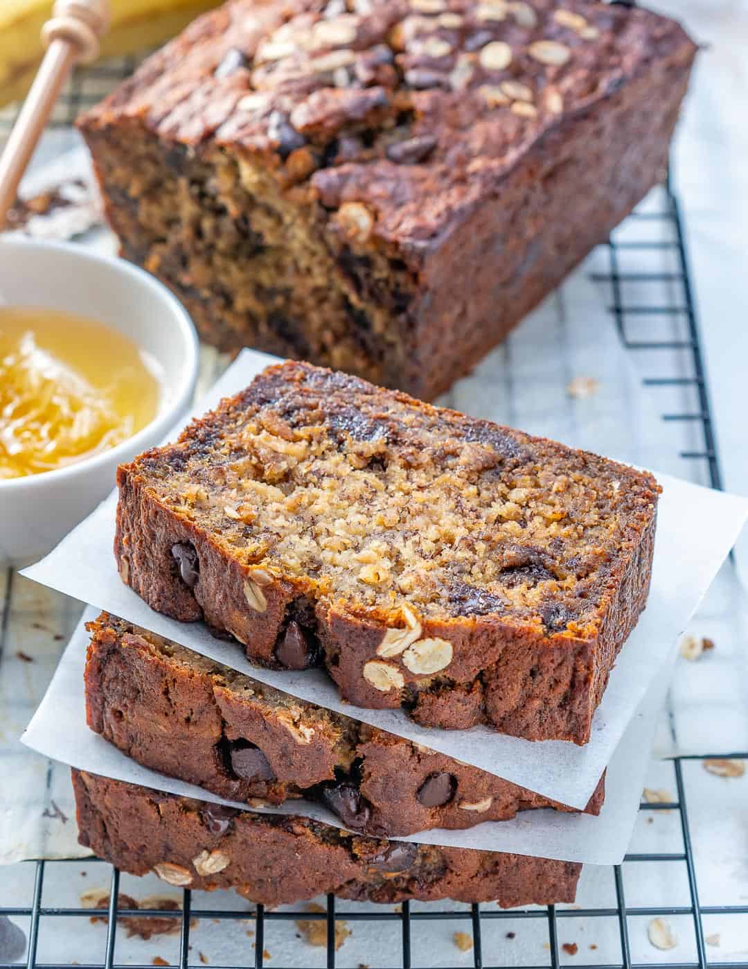 Chocolate Chip Banana Bread stacks over each other on a metal wire wrack.