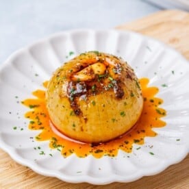 Cooked whole onions with seasonings on a plate.