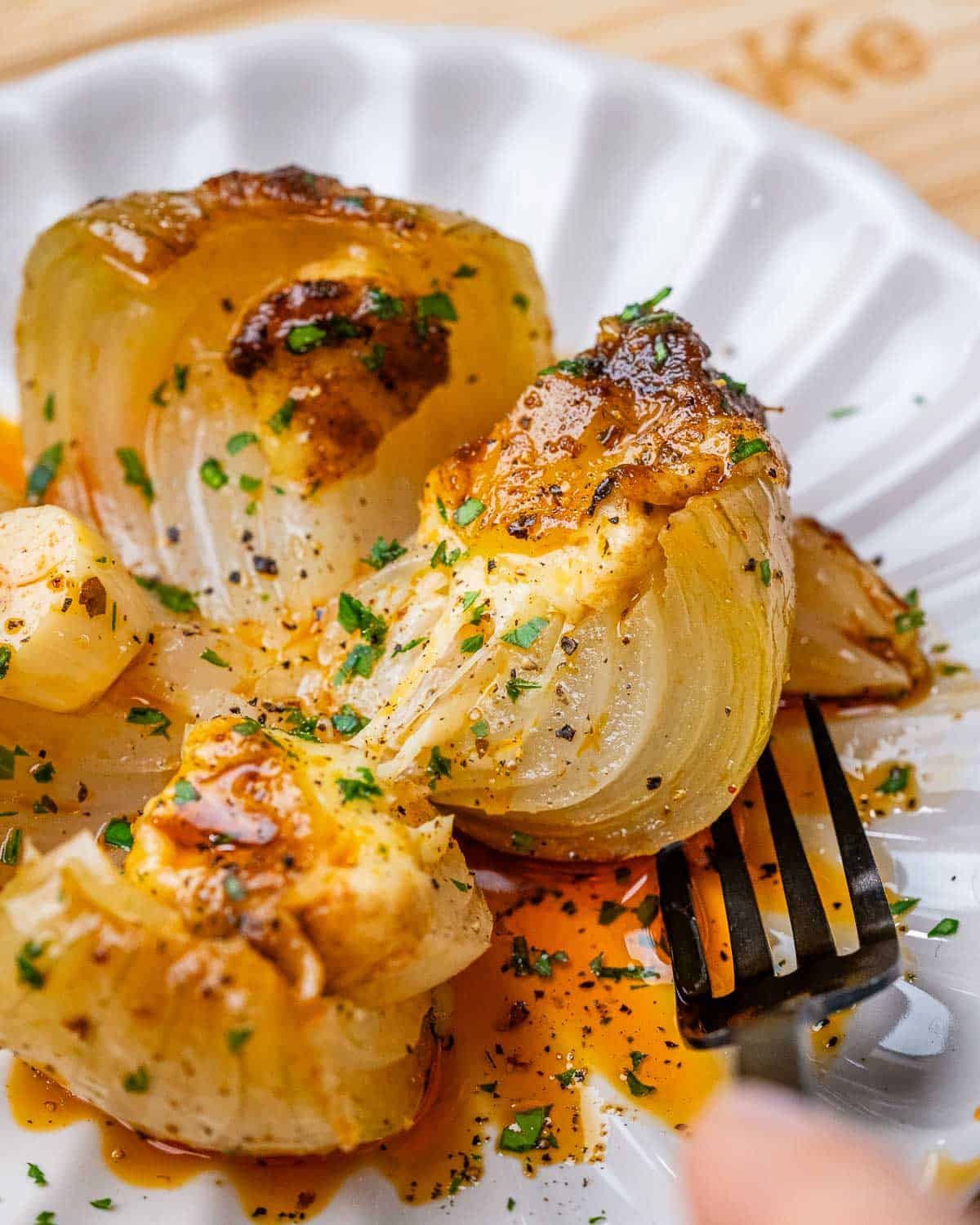 baked onion on a plate cut in the middle with fork on the plate.