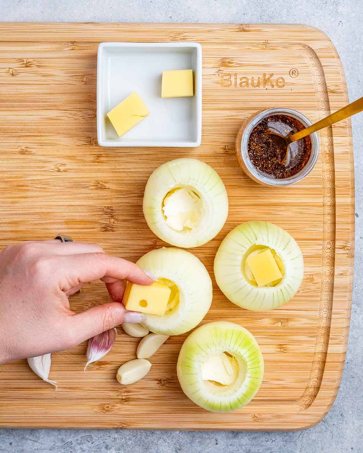 cheese and butter being added to the cored onions.