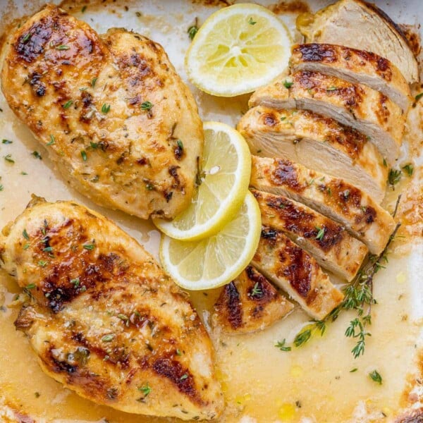 close up of two roasted whole chicken breast and one sliced roasted chicken breast on the right
