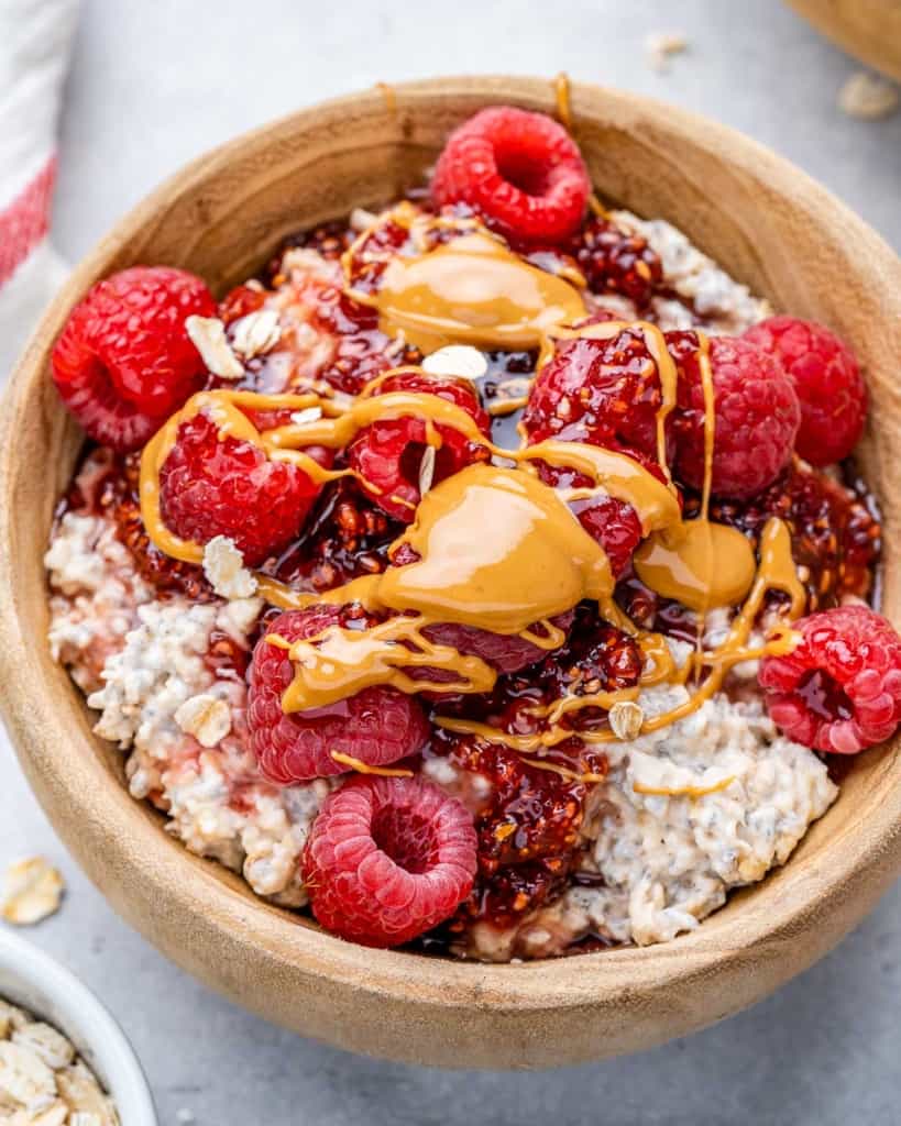 top view overnight oatmeal in a tan bowl topped with raspberry and peanut butter drizzle