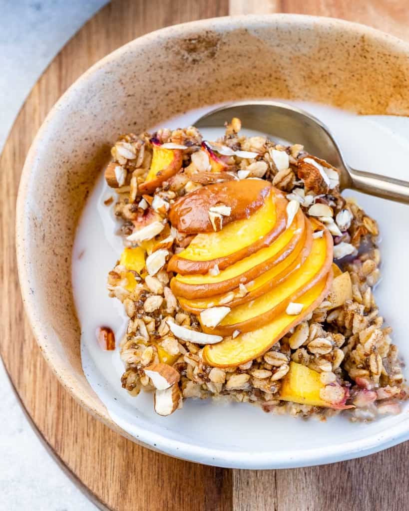 Serving of peach oatmeal bake in a bowl with milk.