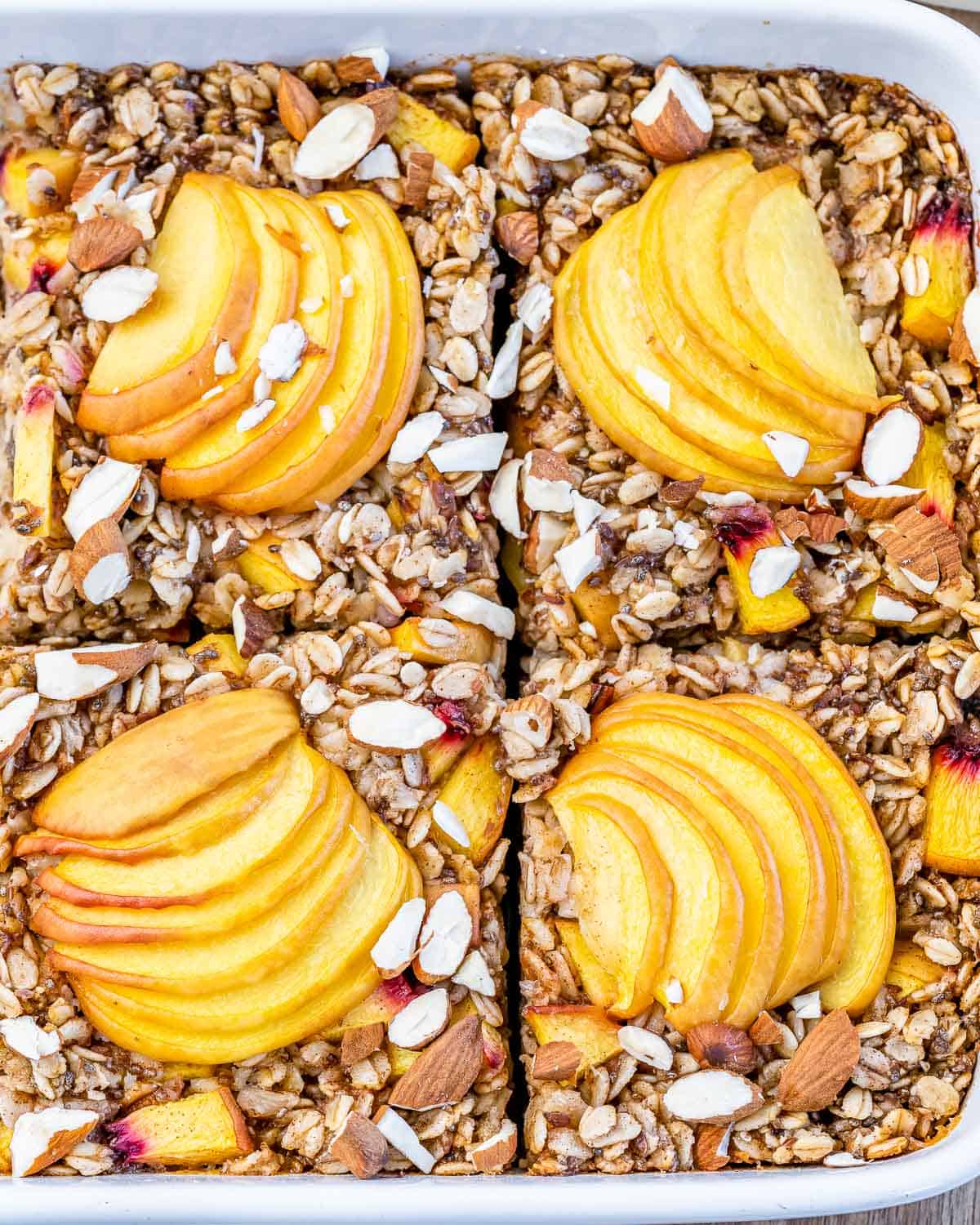 Baked peach oatmeal cut into squares in a baking dish.