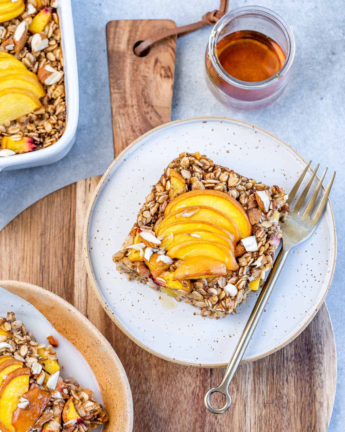 a serving of oatmeal baked with peaches on a plate with a fork on the right side.