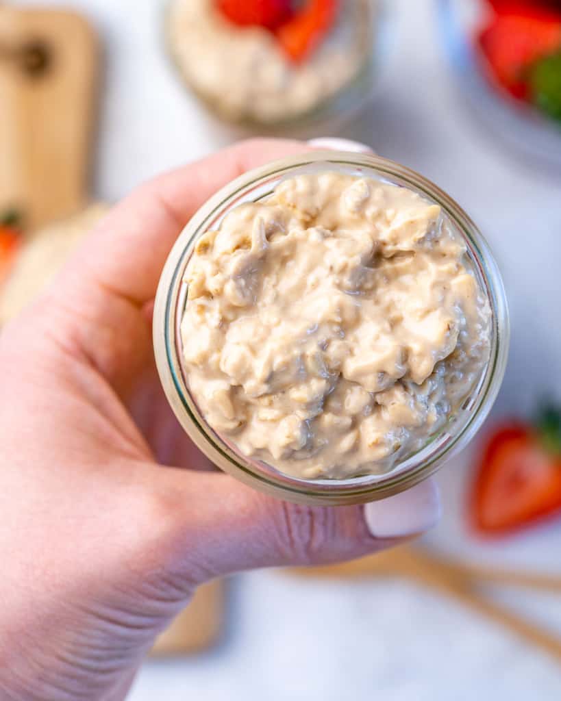 hand holding overnight oats in a jar 