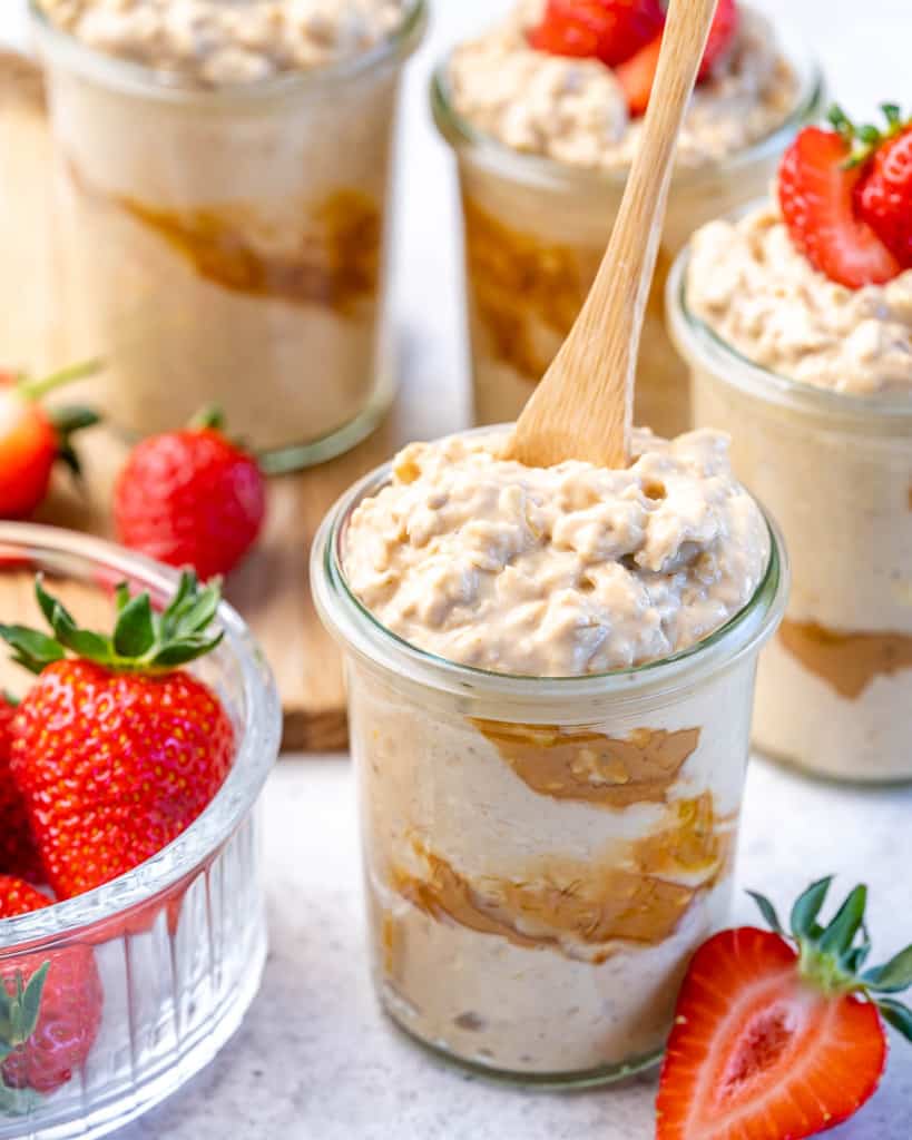 spoon in a jar containing overnight oats with a side of fresh strawberries 