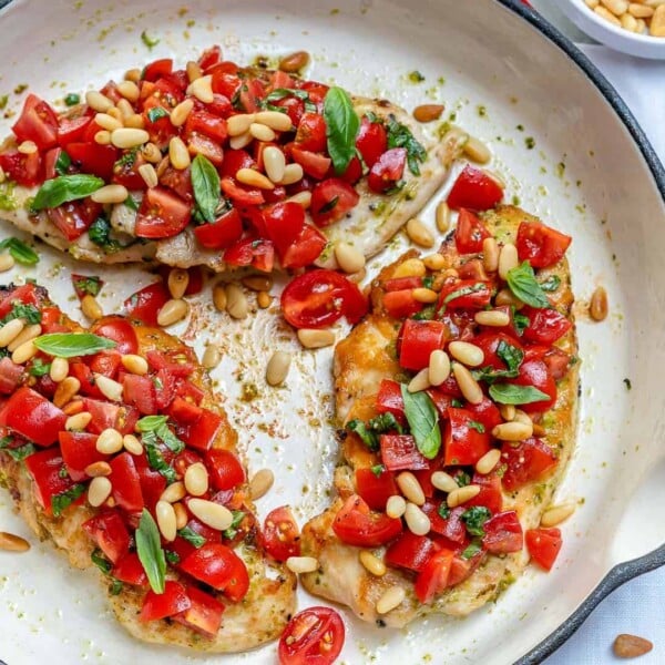 top view of Pesto bruschetta chicken breasts in a skillet topped with chopped tomatoes