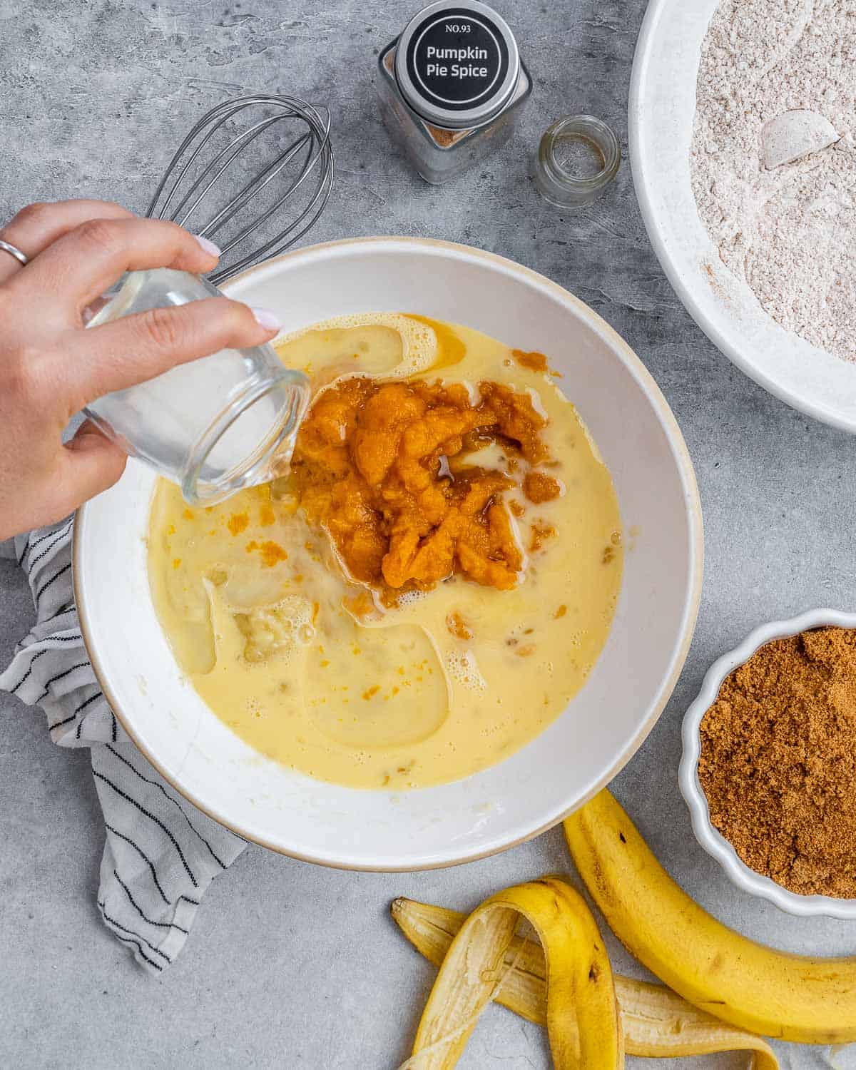 Pouring milk into a bowl with eggs and pumpkin.