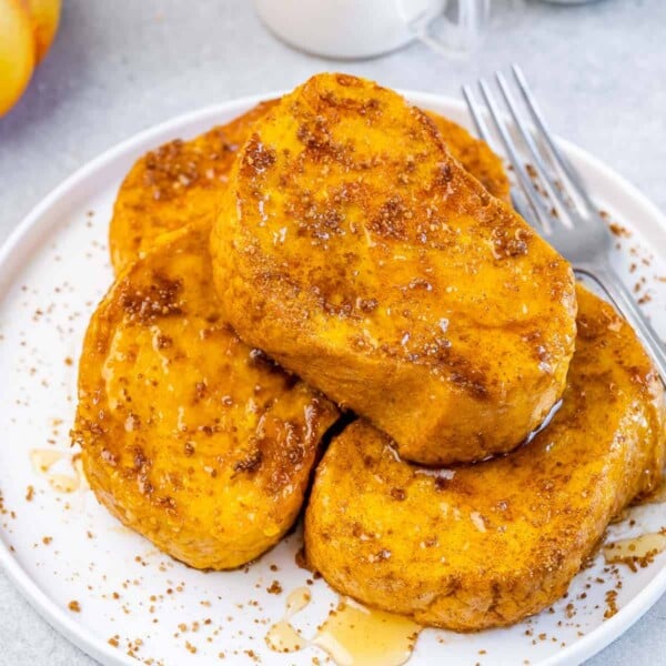4 french toast on a plate with a drizzle of maple syrup over the French toast.