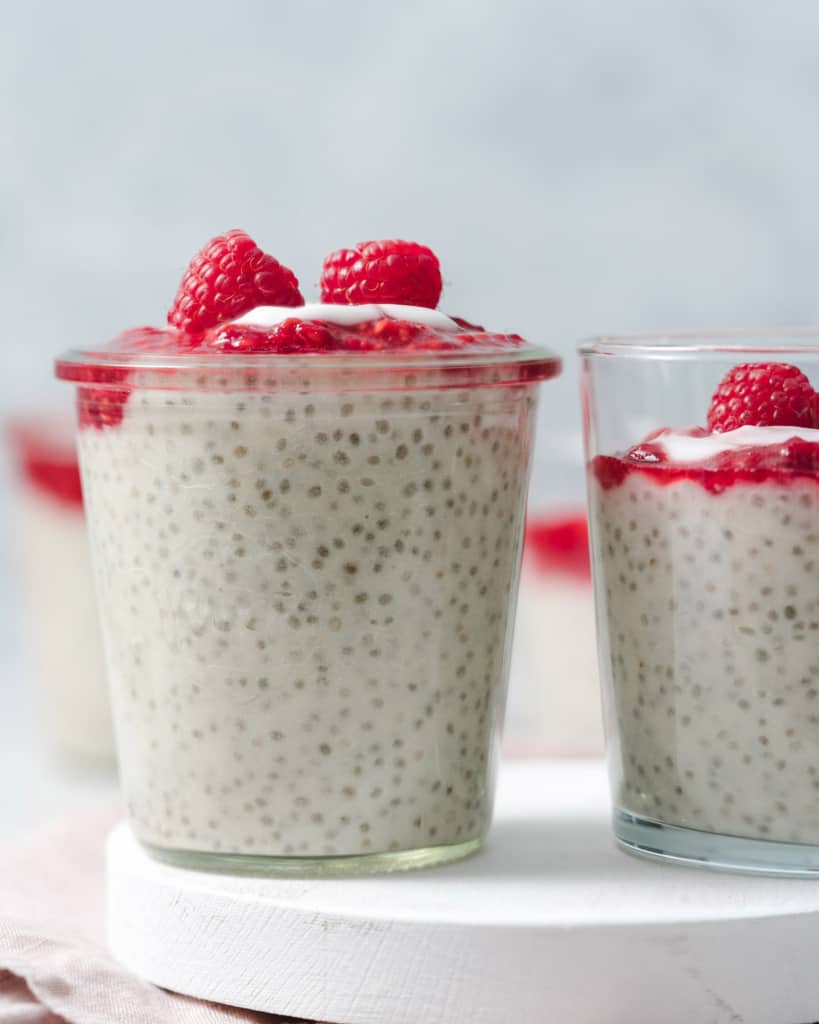 side shot of a jar of yogurt chia pudding topped with mashed raspberries