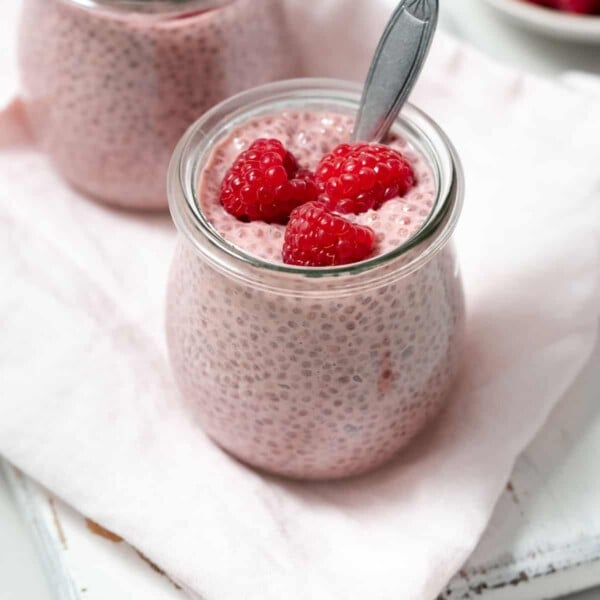 a jar of raspberry chia pudding topped with fresh raspberry.