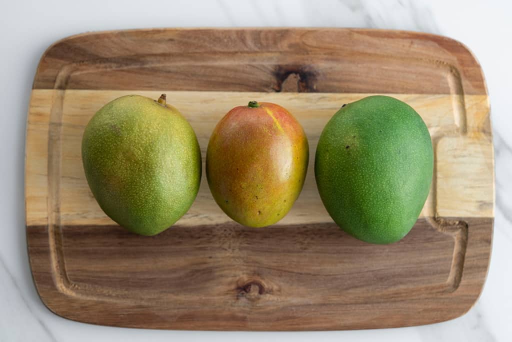 top view of 3 mangos on a cutting board
