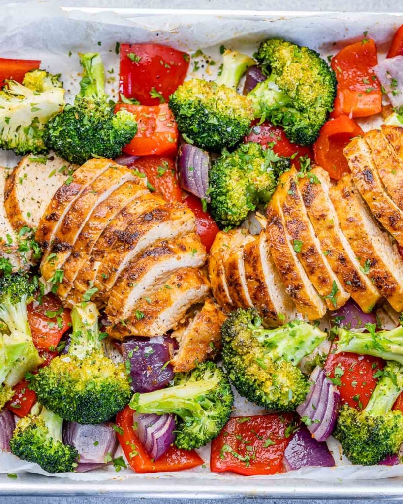 sliced baked chicken breast with roasted veggies on a pan 