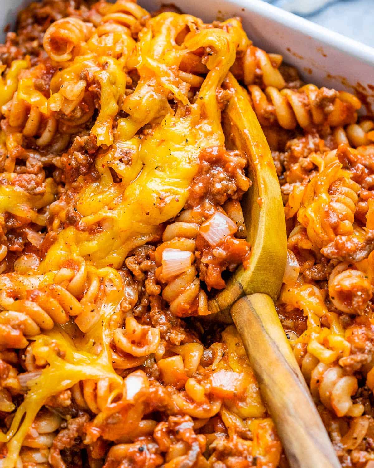 A casserole white dish with rotini pasta in a meaty tomato sauce.