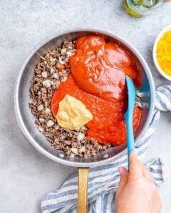 sauce, ketchup, and mustard are added over browned meat in oan.