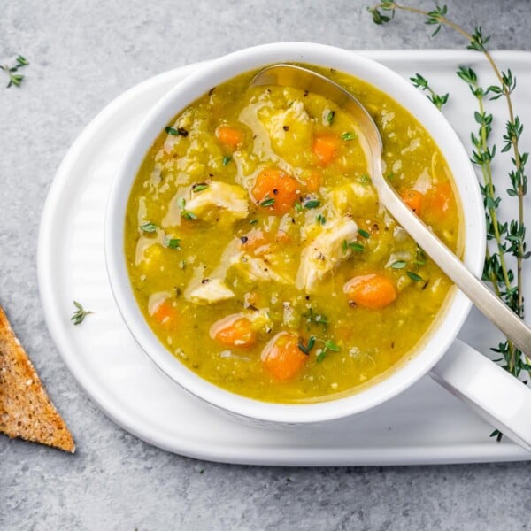 top view of a white round bowl of split pea soup with a spoon in the bowl on the right side
