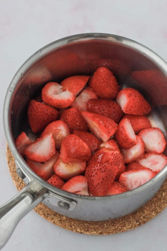 fresh cut strawberries in a pot before mashing 