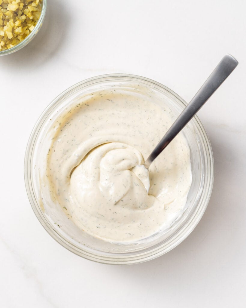 ingredients to make tartar sauce in a bowl mixed with a spoon