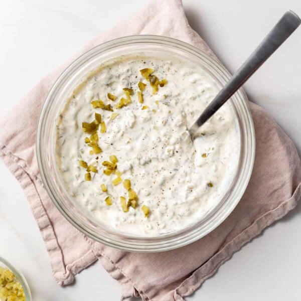 tartar sauce in a clear bowl with a spoon in the bowl.
