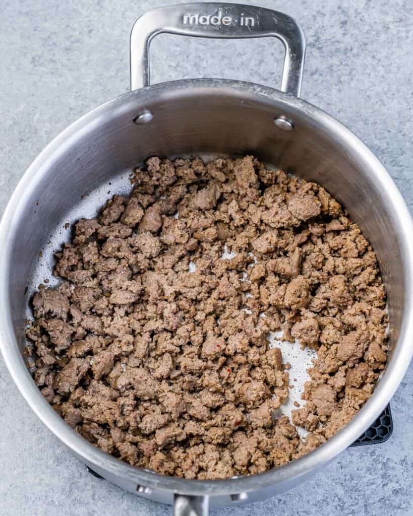Sautéing ground Italian sausage in a large pot.