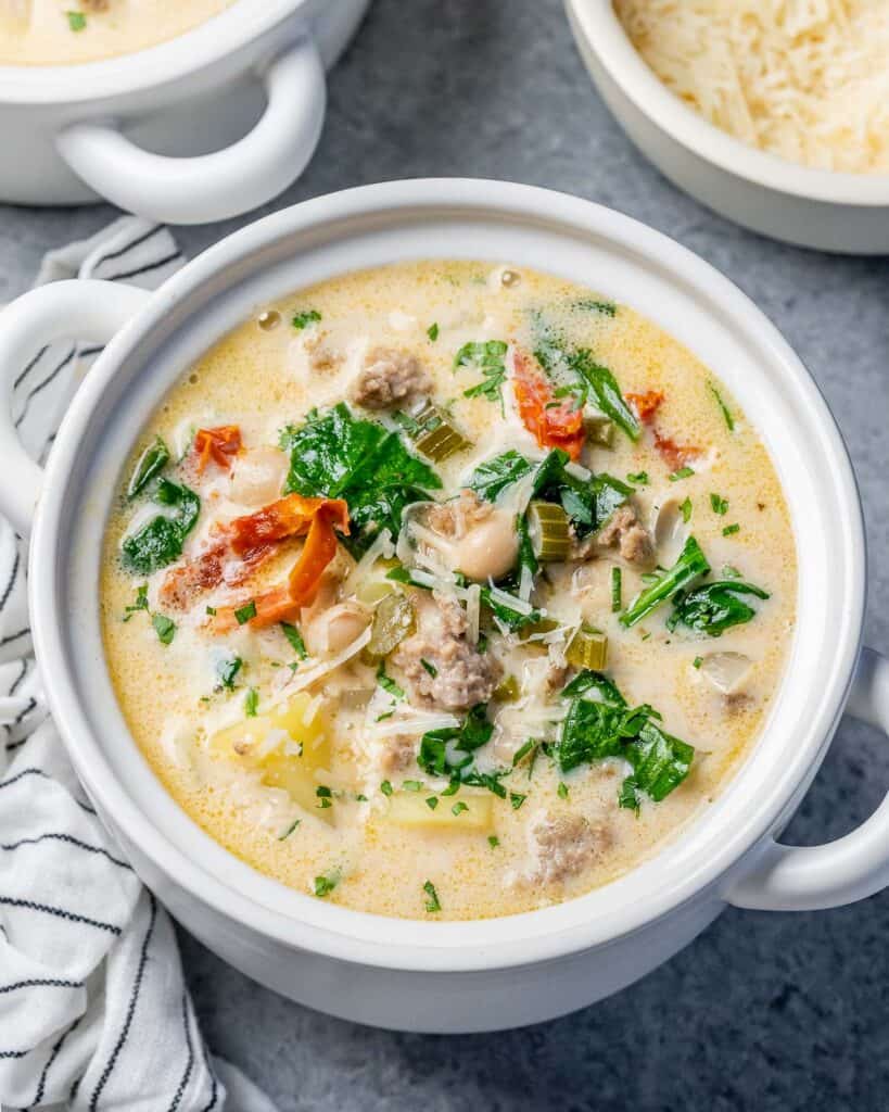 Closeup view of white bean soup topped with sun-dried tomatoes and spinach.