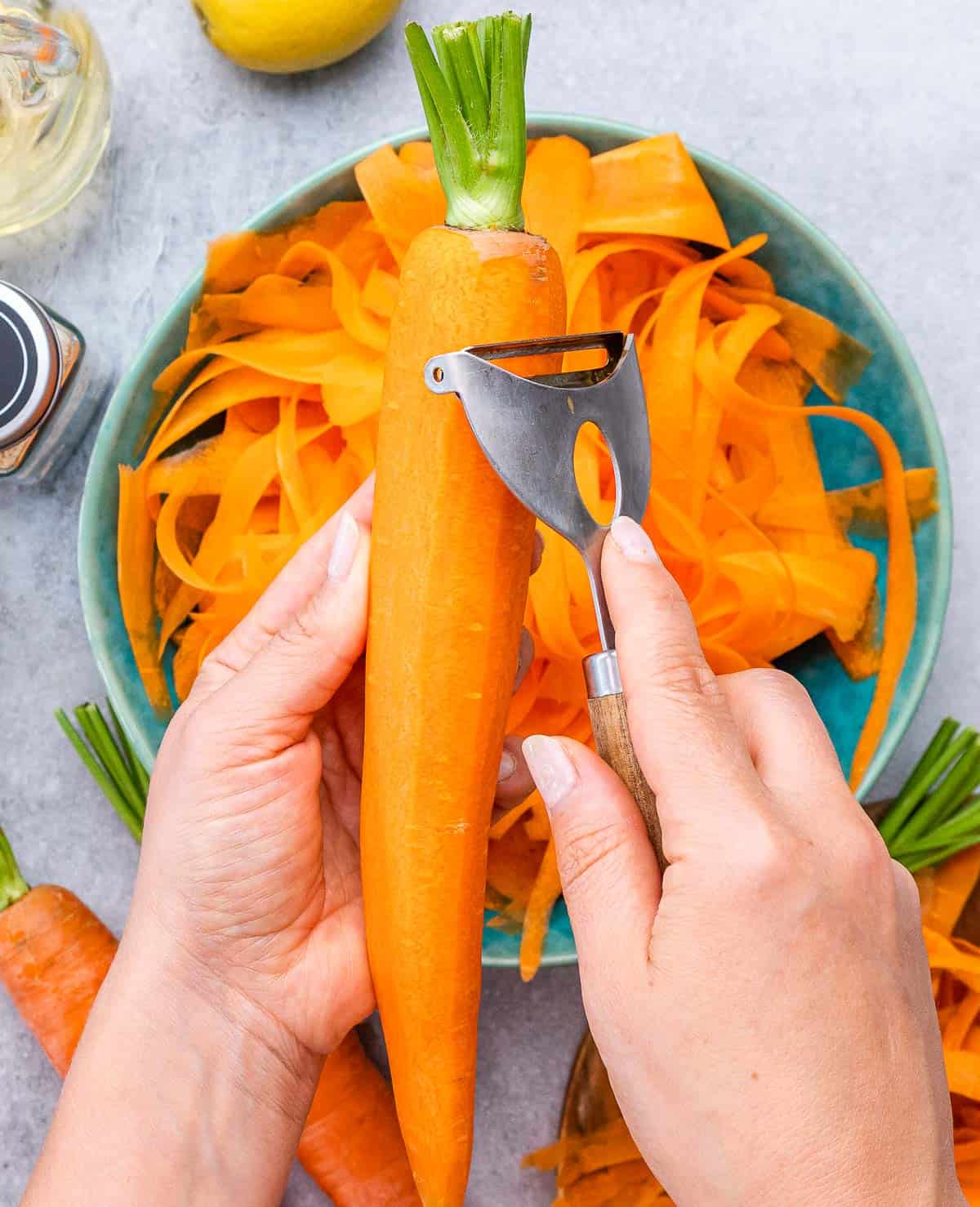 Peeling a carrot into a blue bowl.