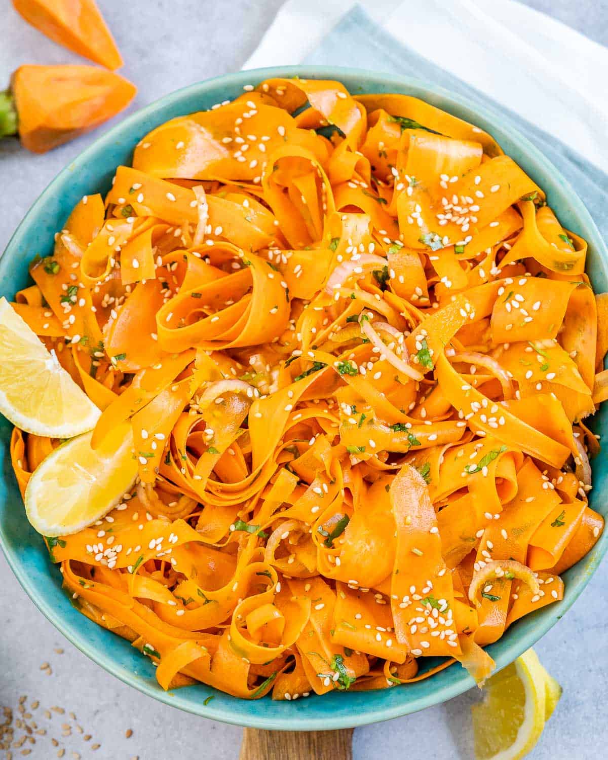 Sliced carrot salad in a round blue bowl.